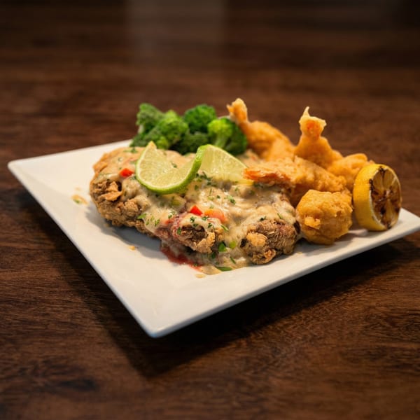 Crispy fried chicken with creamy sauce, lime, broccoli, fried shrimp, and grilled lemon.