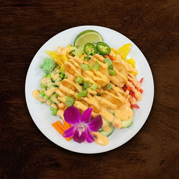 Crispy shrimp drizzled with sauce, green onions, and a purple orchid on a white plate.