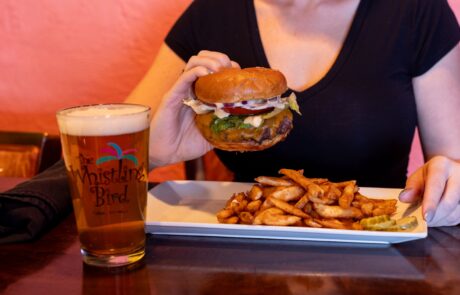 Woman enjoying a burger and a beer at the Whistling Bird