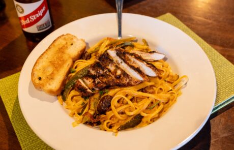 Rasta pasta dish with Chicken and a side of garlic bread